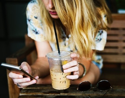 ドリンクを持ってスマホ操作する女性